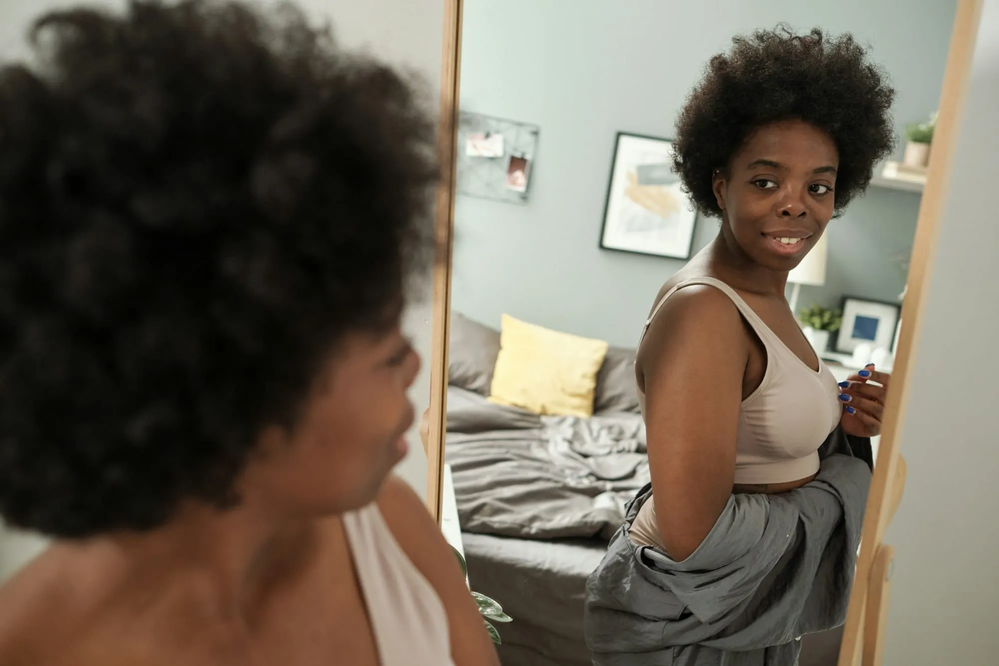 Young smiling woman in underwear looking in mirror